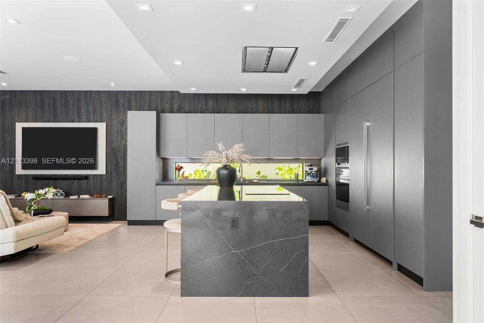 6814 NW 104th Court, #6814, Doral, Doral, FL 33178 Modern kitchen featuring a central island with a waterfall edge, floor-to-ceiling flat-panel cabinetry, a horizontal ribbon window, integrated built-in appliances, and large-format tile flooring