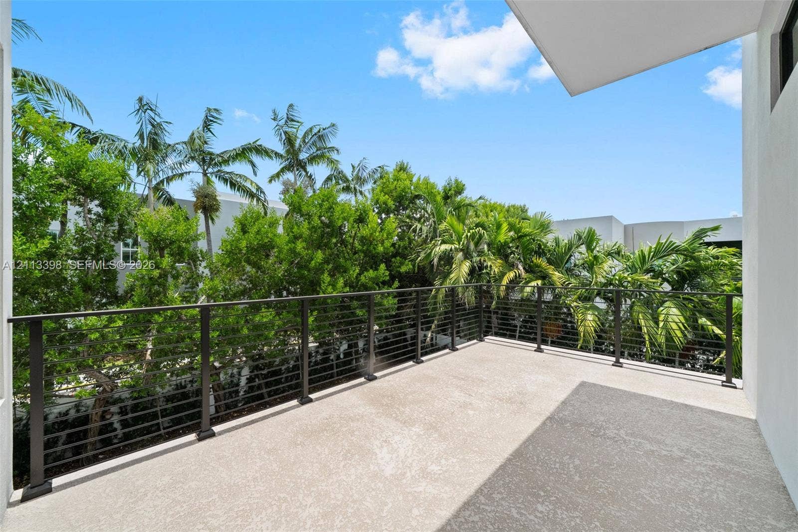 6814 NW 104th Court, #6814, Doral, Doral, FL 33178 Covered balcony featuring concrete flooring, a dark metal cable railing, and dense mature palms