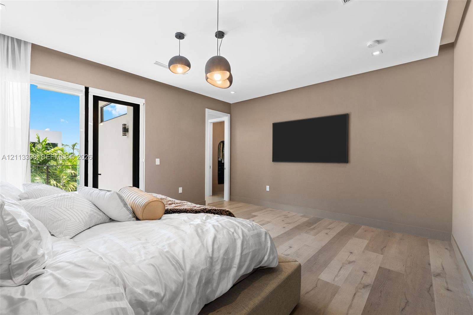 6814 NW 104th Court, #6814, Doral, Doral, FL 33178 Room featuring wood-finish flooring, dual metal globe pendant lights, and floor-to-ceiling glass door access to an exterior terrace