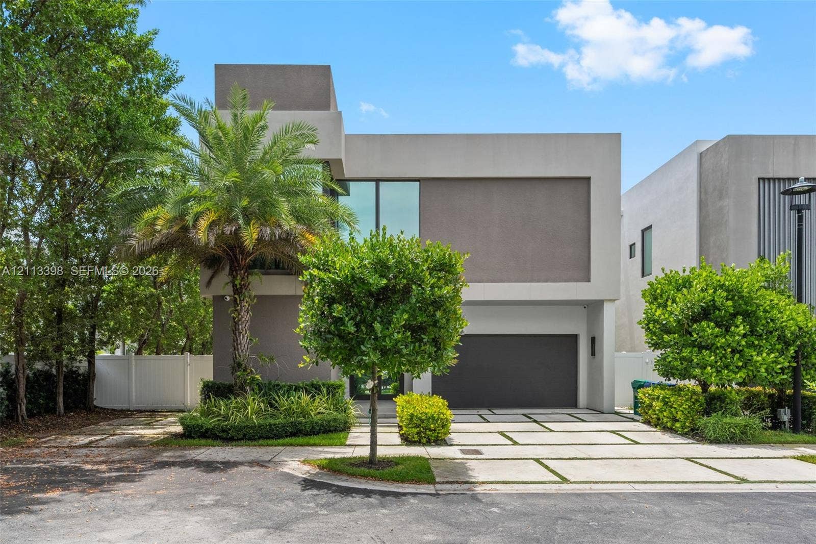 6814 NW 104th Court, #6814, Doral, Doral, FL 33178 Contemporary two-story exterior featuring a smooth stucco facade, floor-to-ceiling windows, attached two-car garage, and a geometric concrete paver driveway