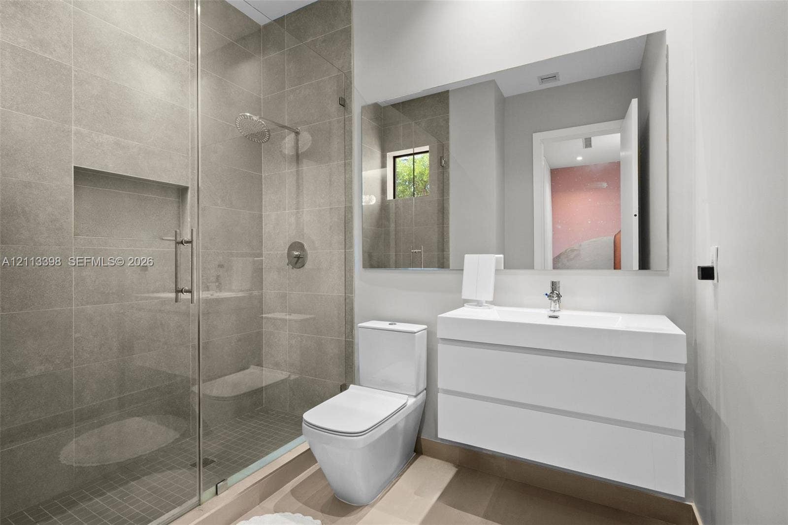 6814 NW 104th Court, #6814, Doral, Doral, FL 33178 Modern bathroom featuring a glass-enclosed shower with tiled walls and a built-in recessed niche, a white floating vanity with a seamless integrated sink, and a wall-to-wall mirror
