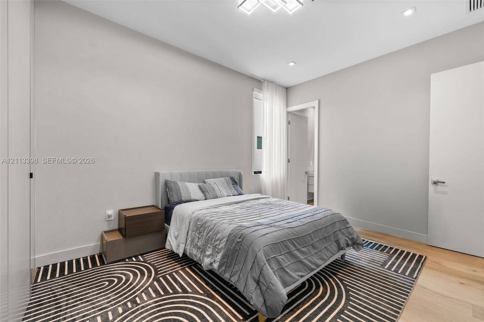 6814 NW 104th Court, #6814, Doral, Doral, FL 33178 Neutral-toned bedroom featuring wood-finish flooring, recessed lighting, a modern geometric ceiling light fixture, and floor-to-ceiling cabinetry