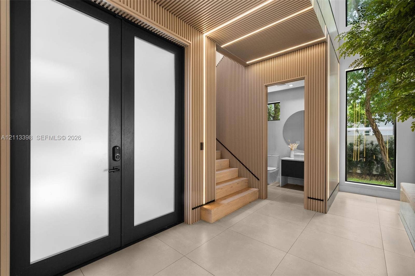 6814 NW 104th Court, #6814, Doral, Doral, FL 33178 Double-entry door with frosted glass panels, wood-slat wall paneling with integrated LED lighting, large-format tile flooring, and a floating staircase
