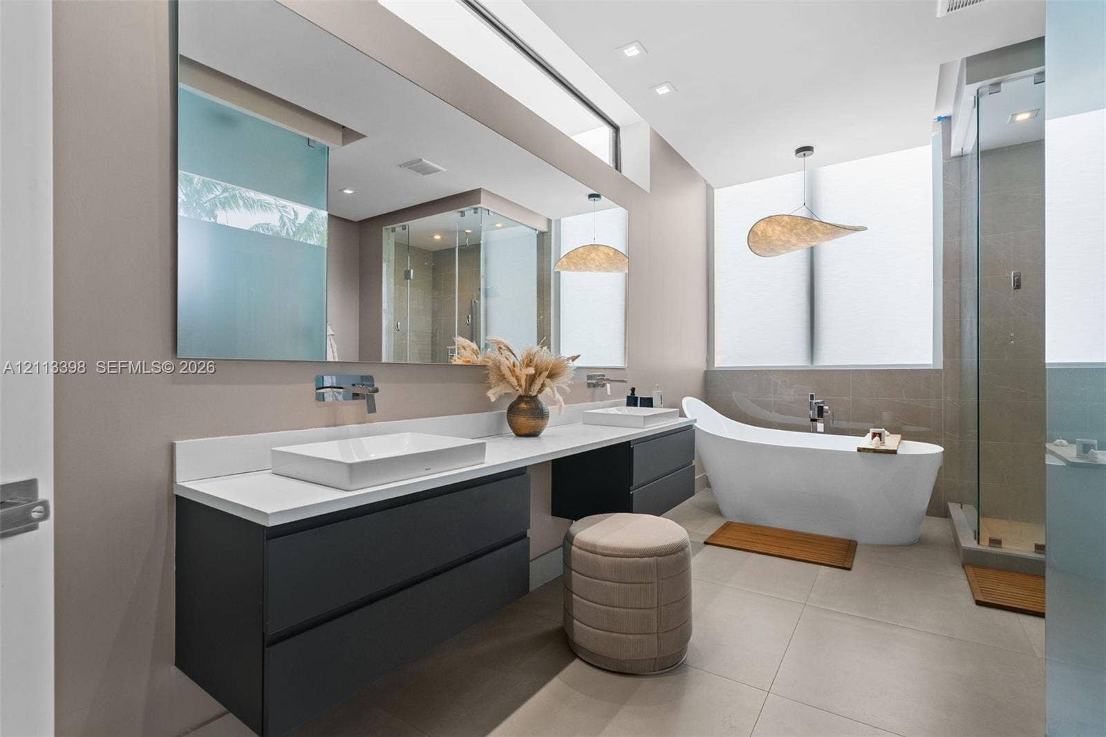 6814 NW 104th Court, #6814, Doral, Doral, FL 33178 Floating dual-vanity with rectangular vessel sinks, quartz countertop, wall-mounted faucets, freestanding soaking tub, and glass-enclosed shower with large-format tile flooring