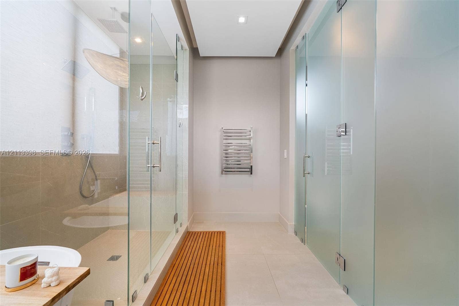 6814 NW 104th Court, #6814, Doral, Doral, FL 33178 Walk-in shower featuring a glass enclosure, floor-to-ceiling frosted glass partitioning, recessed ceiling lighting, wall-mounted heated towel rack, and a slatted wood floor inlay