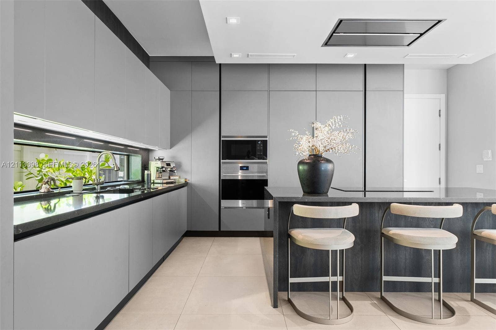 6814 NW 104th Court, #6814, Doral, Doral, FL 33178 Modern kitchen featuring matte grey flat-panel cabinetry, dark stone countertops, built-in stainless steel appliances, a horizontal window backsplash, and a ceiling-mounted ventilation hood