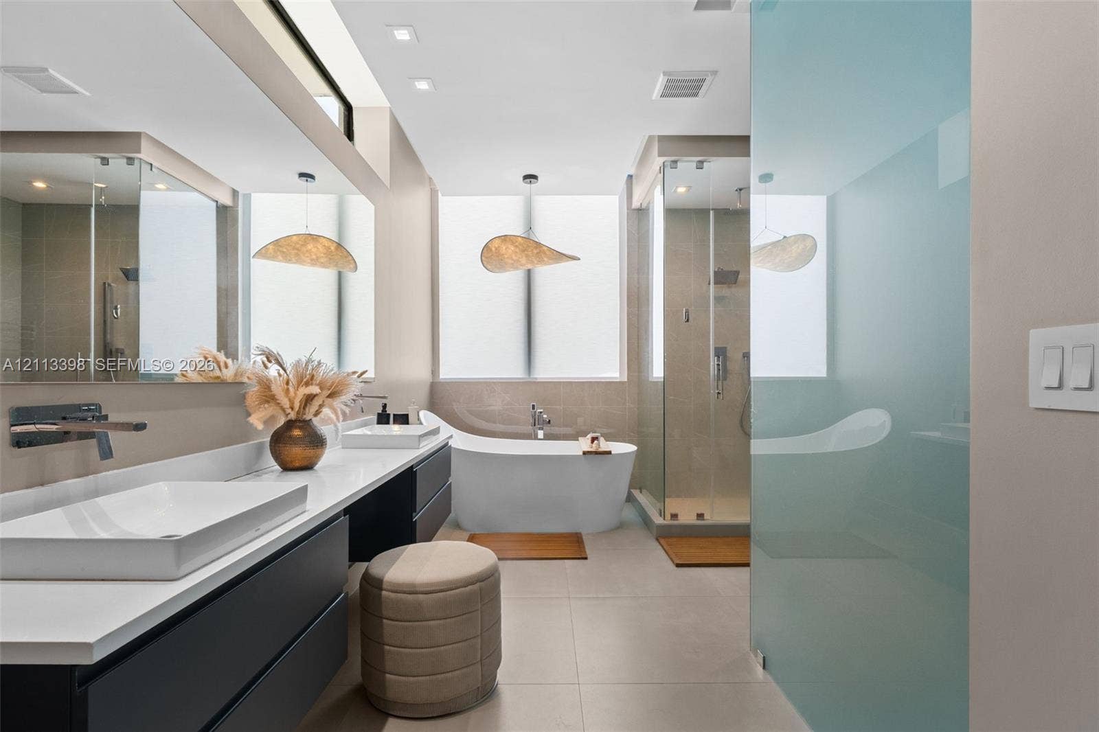 6814 NW 104th Court, #6814, Doral, Doral, FL 33178 Modern bathroom featuring a floating dual vanity with rectangular vessel sinks, wall-mounted faucets, a freestanding soaking tub, and a glass-enclosed shower with tiled walls