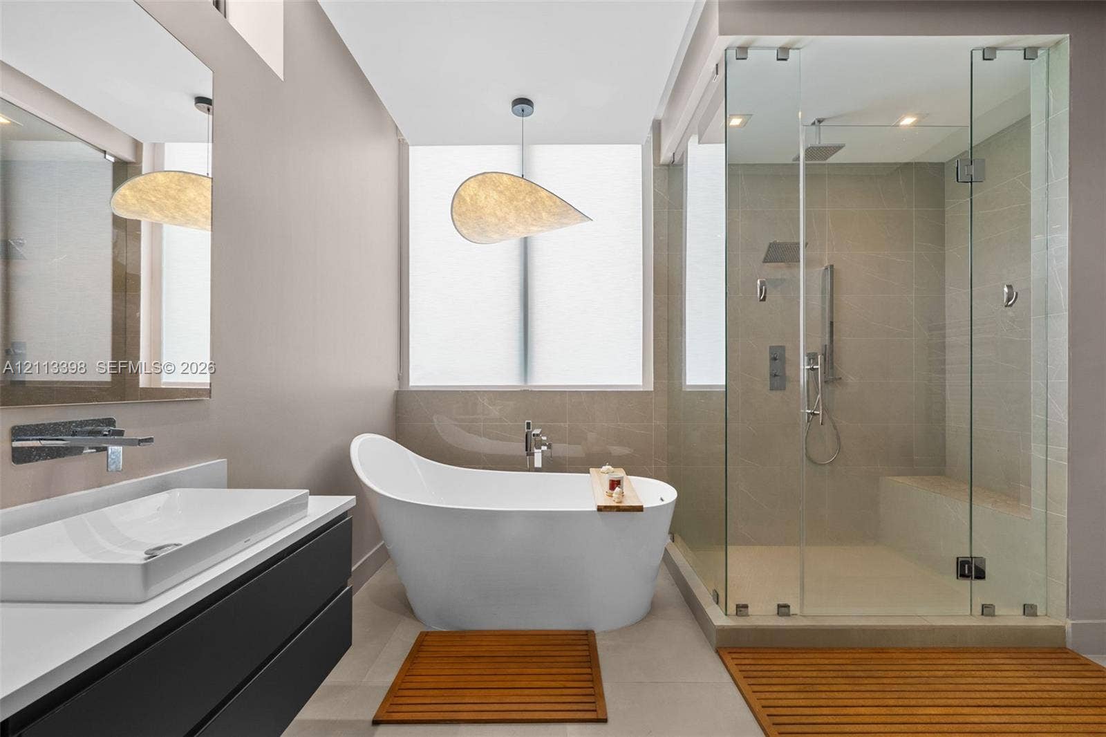 6814 NW 104th Court, #6814, Doral, Doral, FL 33178 Modern floating vanity with a vessel sink and wall-mounted faucet, freestanding soaking tub, glass-enclosed walk-in shower with a built-in bench, and large-format tile flooring