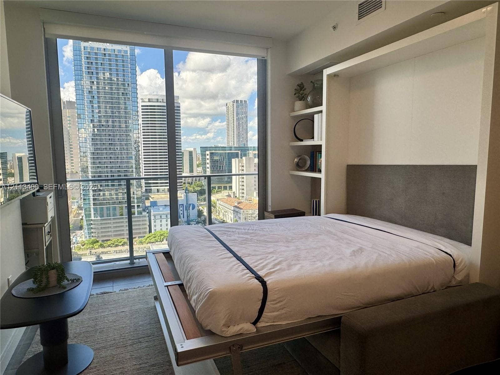 227 NE 2nd Street, #2105, Miami, FL 33132 Floor-to-ceiling windows, built-in shelving, retractable bed system, and private balcony with metropolitan backdrop