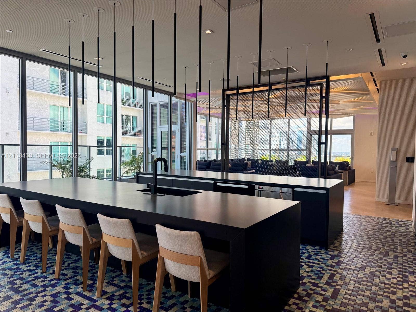 227 NE 2nd Street, #2105, Miami, FL 33132 Expansive kitchen island featuring a dark solid-surface countertop, integrated basin, and matte black faucet, illuminated by a series of minimalist pendant lights