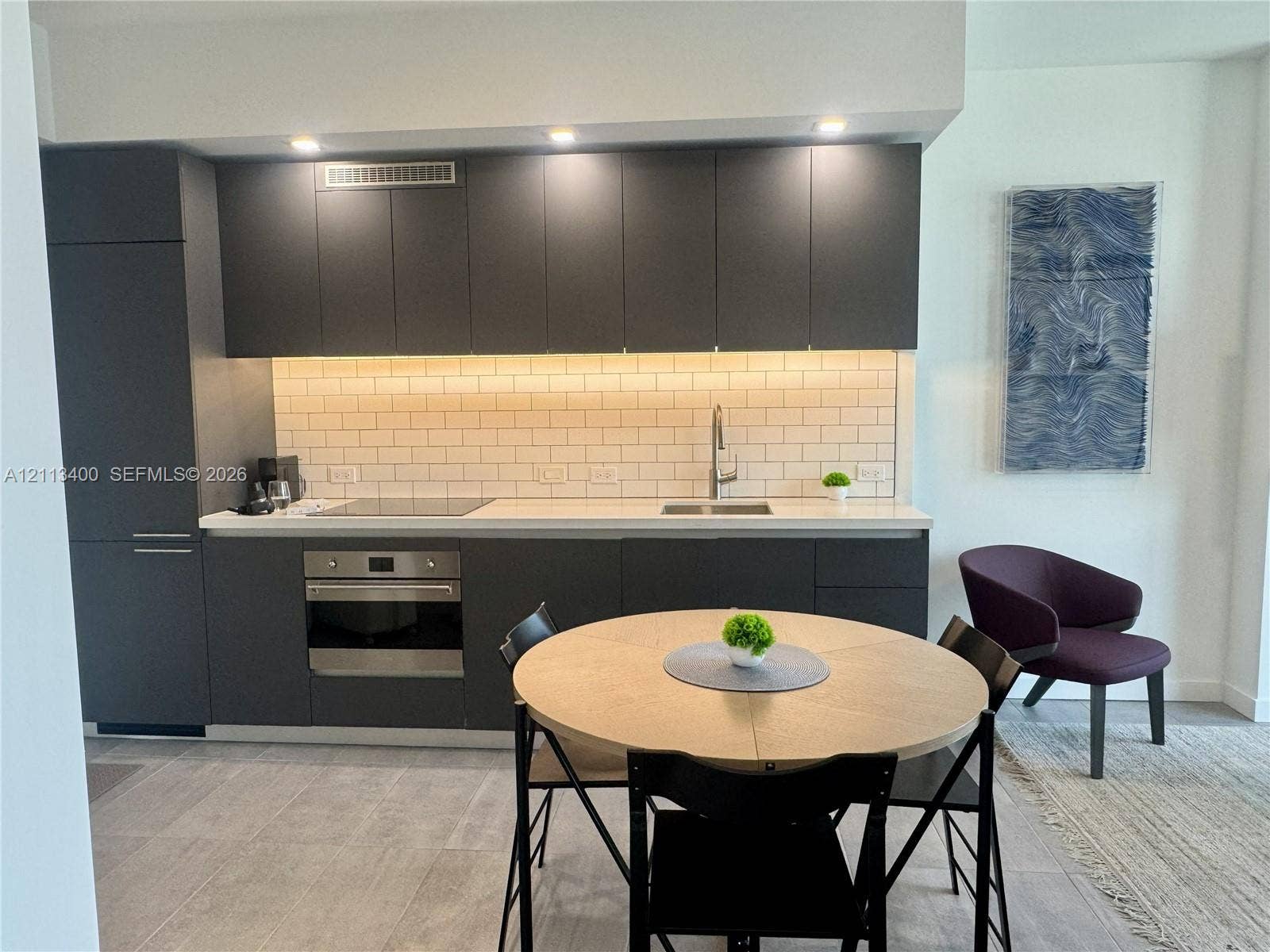 227 NE 2nd Street, #2105, Miami, FL 33132 Kitchen featuring matte charcoal flat-panel cabinetry, light-toned countertop, subway tile backsplash, built-in stainless steel oven, and recessed lighting