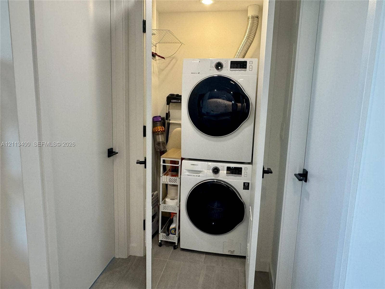 227 NE 2nd Street, #2105, Miami, FL 33132 Laundry closet featuring stacked high-efficiency washer and dryer, tile flooring, and matte black door hardware