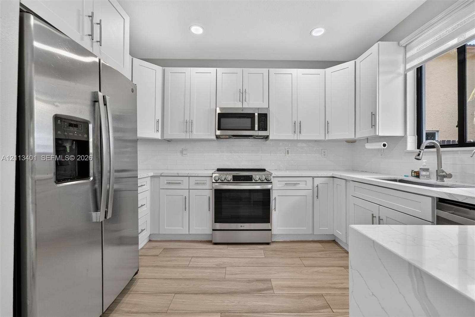 15891 SW 139th Street, Miami, Miami, FL 33196 Kitchen featuring white Shaker-style cabinetry, stainless steel appliances, quartz countertops with a subtle veining pattern, white subway tile backsplash, and wood-finish flooring