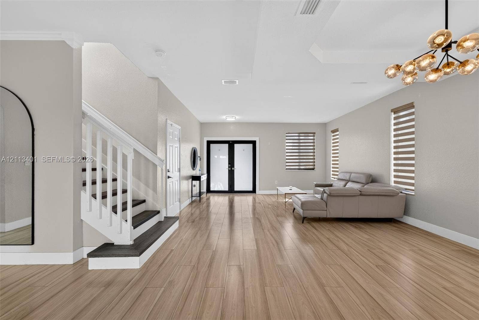 15891 SW 139th Street, Miami, Miami, FL 33196 Wood-finish flooring, white staircase with dark treads, tray ceiling, multi-bulb chandelier, and glass-paneled double entry doors