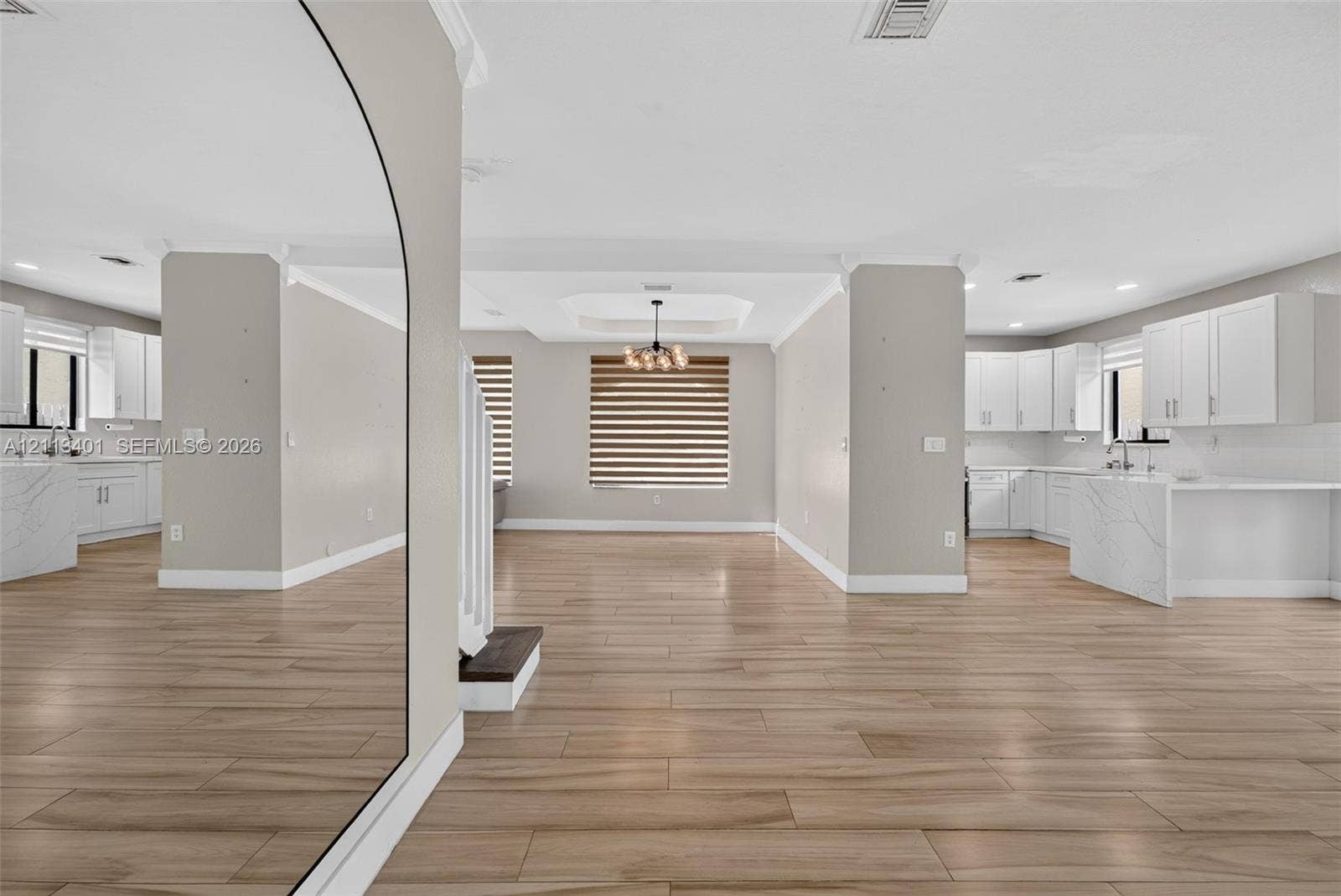 15891 SW 139th Street, Miami, Miami, FL 33196 Open-concept interior featuring wood-finish tile flooring, white cabinetry with stone-finish waterfall countertops, recessed lighting, and a modern tiered tray ceiling