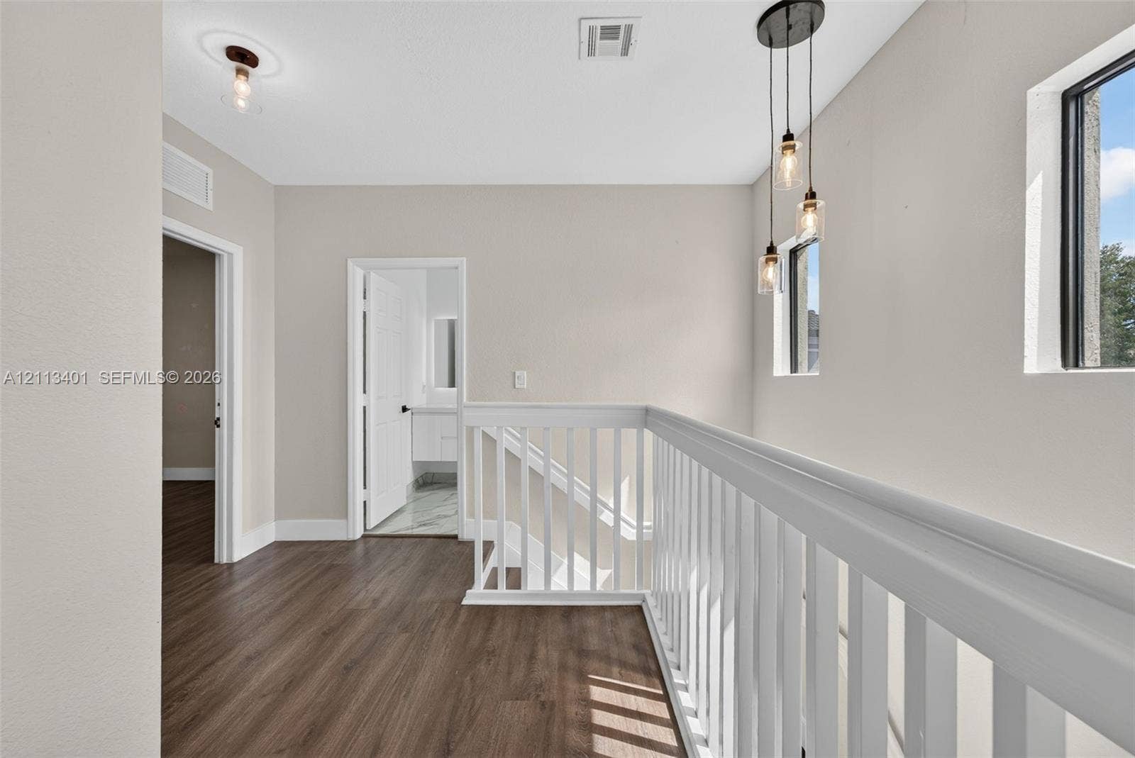 15891 SW 139th Street, Miami, Miami, FL 33196 Hallway featuring wood-finish flooring, white railing with vertical balusters, trio pendant lighting, and neutral wall tones