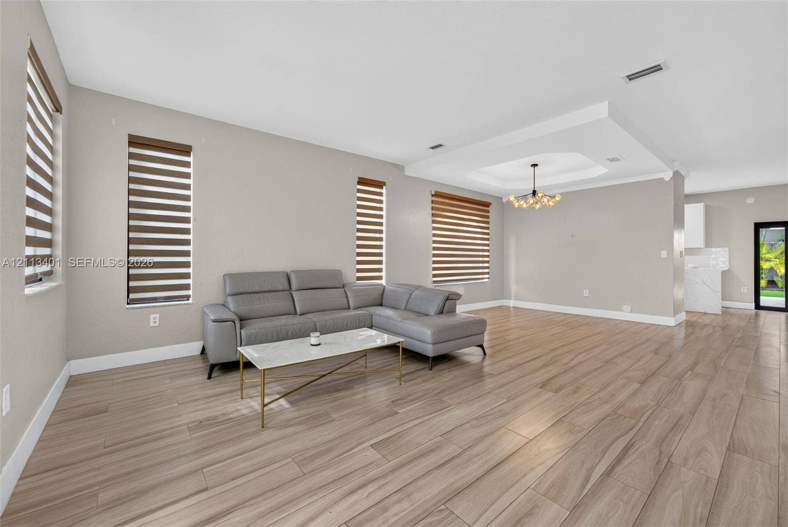 15891 SW 139th Street, Miami, Miami, FL 33196 Open concept interior featuring wood-finish tile flooring, recessed tray ceiling, multi-light chandelier, and horizontal window shades