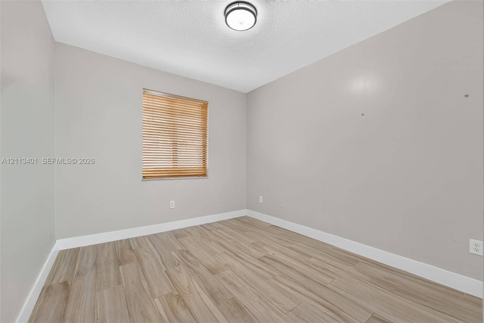 15891 SW 139th Street, Miami, Miami, FL 33196 Room featuring neutral-toned walls, wood-finish flooring, a single window with wood-finish blinds, and a circular flush-mount ceiling light fixture
