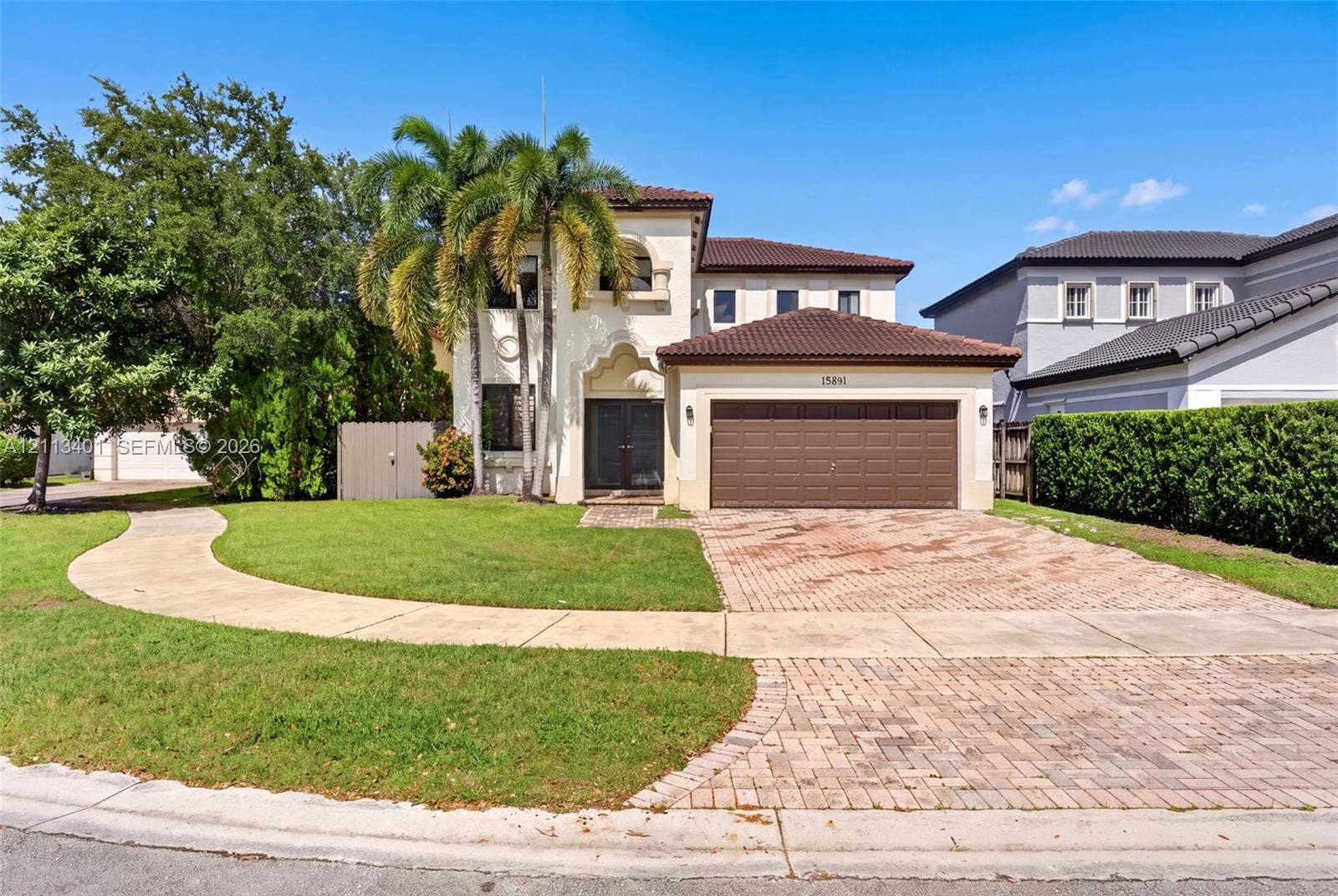 15891 SW 139th Street, Miami, Miami, FL 33196 Two-story stucco exterior featuring a tiled roof, arched entryway, brick-paver driveway, and an attached two-car garage