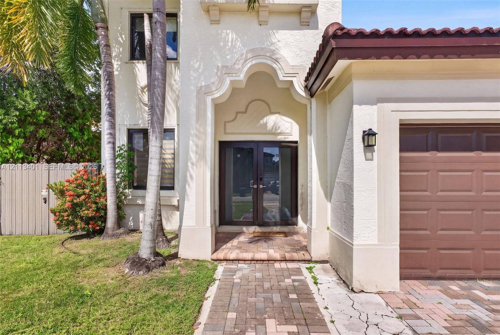 15891 SW 139th Street, Miami, Miami, FL 33196 Stucco exterior featuring an arched entryway with double glass-paneled doors, a tiled roof, and a brick-paver walkway