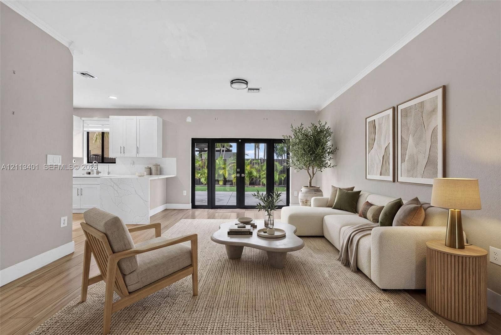15891 SW 139th Street, Miami, Miami, FL 33196 Open-concept living space featuring wood-finish flooring, white kitchen cabinetry, a waterfall-edge stone island, and black-framed French doors