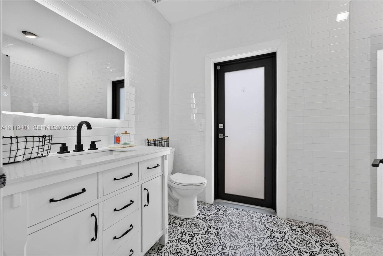 15891 SW 139th Street, Miami, Miami, FL 33196 White vanity with a light-toned countertop, matte black hardware, integrated backsplash, backlit mirror, and patterned tile flooring