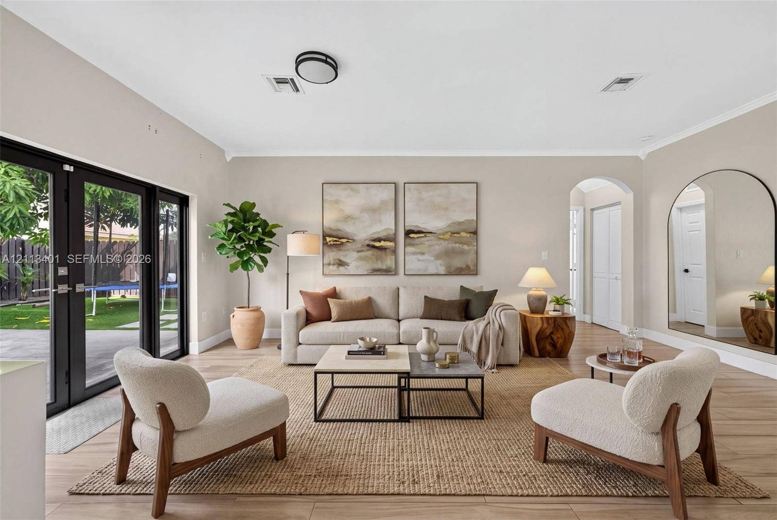 15891 SW 139th Street, Miami, Miami, FL 33196 Neutral-toned interior featuring wood-finish flooring, dual black-framed glass panel doors, and an arched entryway