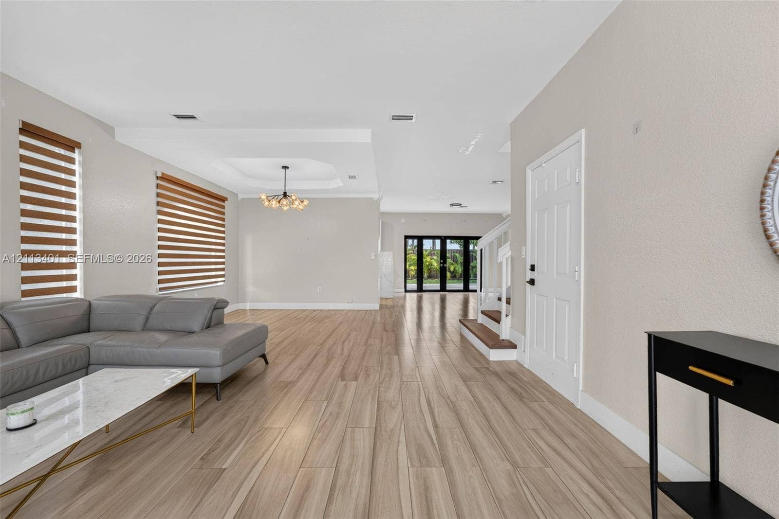 15891 SW 139th Street, Miami, Miami, FL 33196 Open floor plan featuring wood-finish flooring, tray ceiling, statement chandelier, and double-paned sliding glass doors