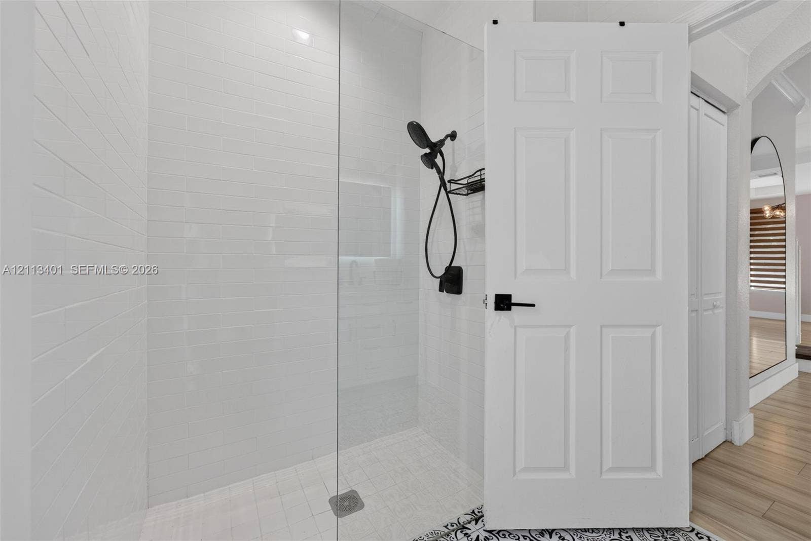 15891 SW 139th Street, Miami, Miami, FL 33196 Walk-in shower with white subway tile surround, glass partition, matte black handheld shower fixture, and wood-finish flooring