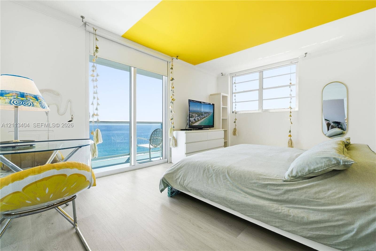 Floor-to-ceiling sliding glass door, white wood-finish flooring, accent-painted ceiling, and horizontal pane windows