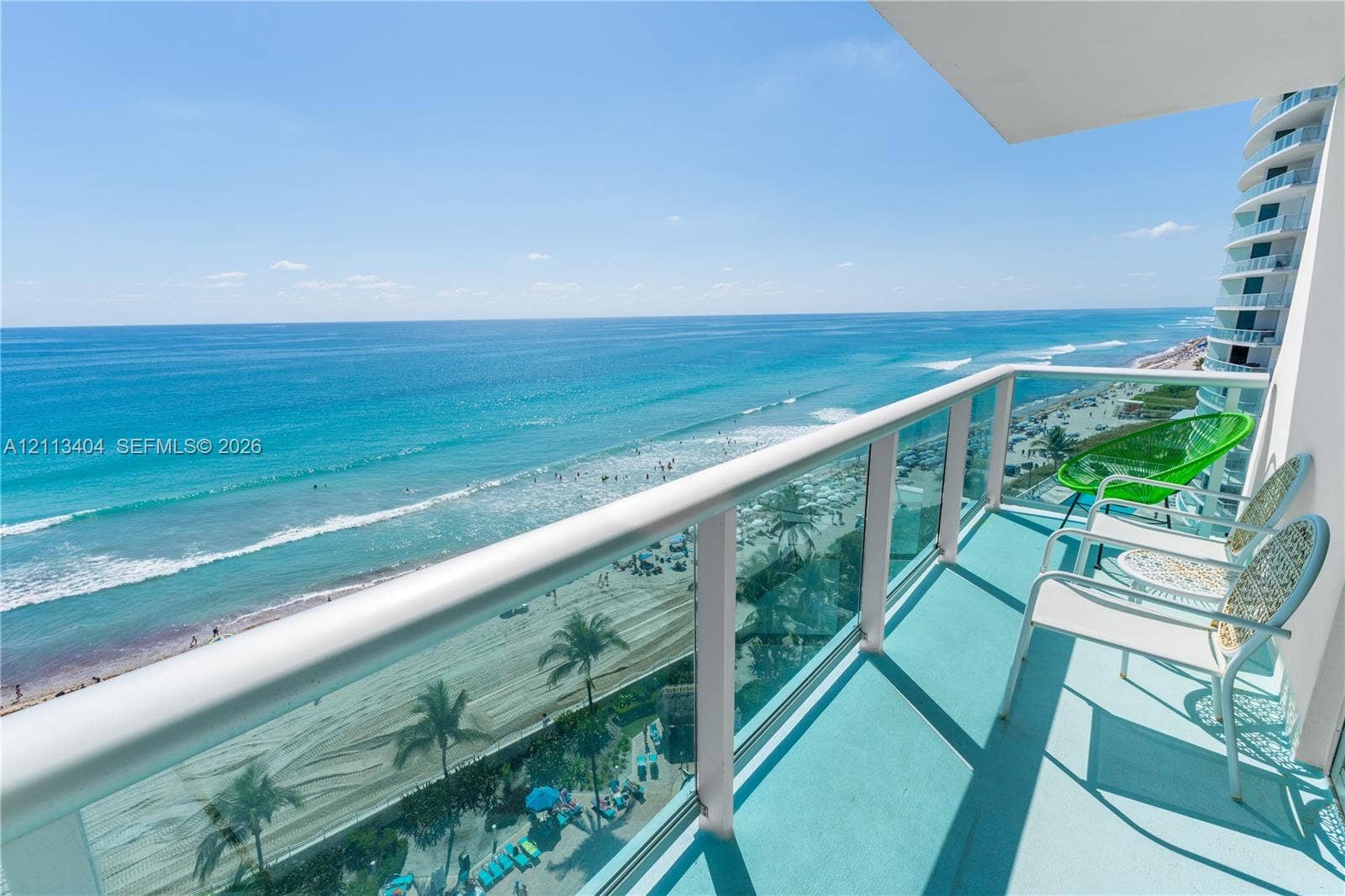 Private balcony featuring a glass-panel railing and elevated oceanfront exposure