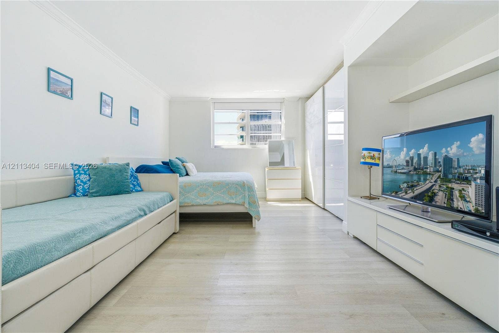 Light-filled interior featuring wood-finish flooring, built-in floor-to-ceiling cabinetry, and custom wall-mounted shelving