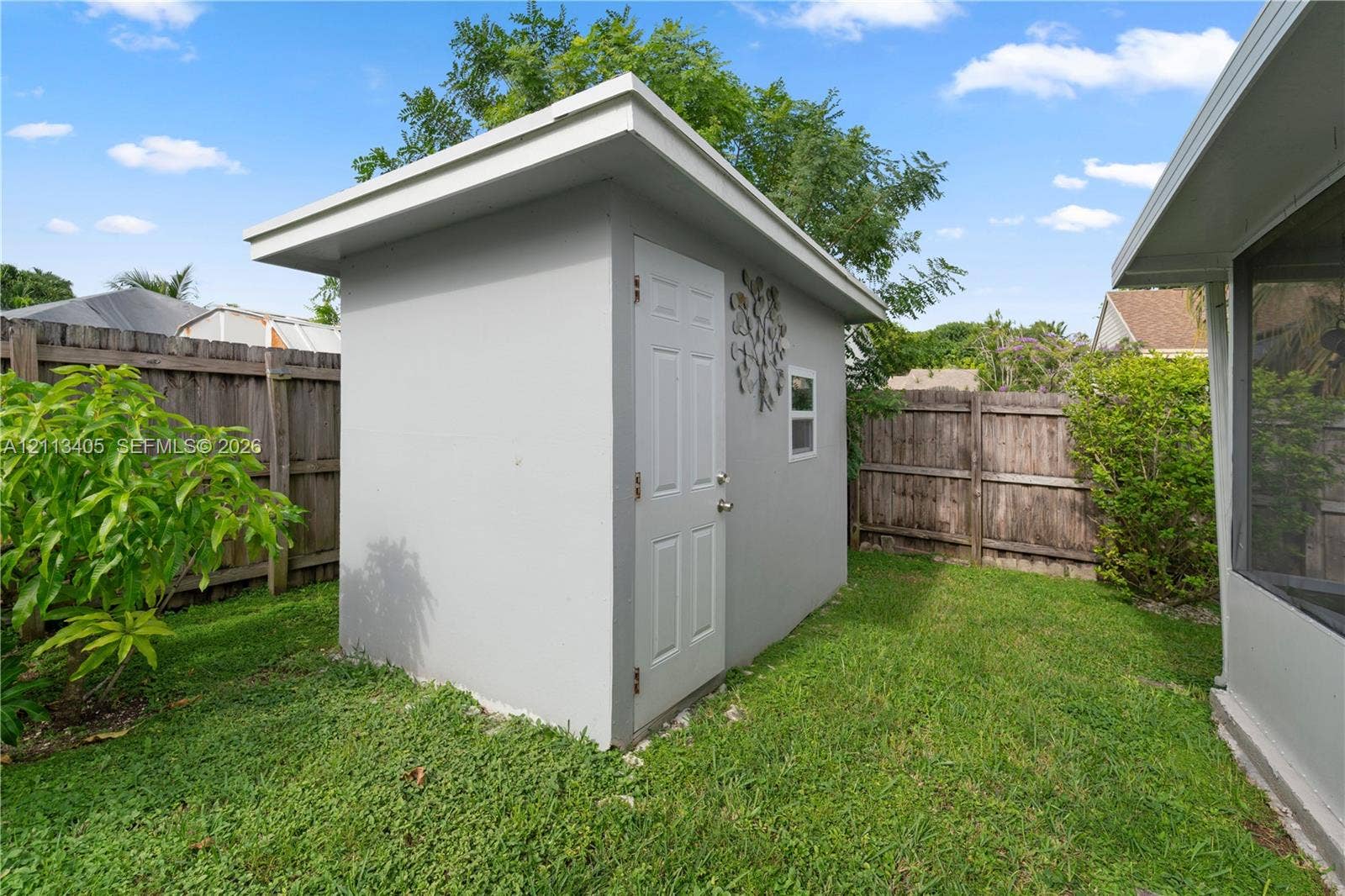 1675 S Goldeneye Lane, Homestead, FL 33035 Detached exterior storage structure featuring a shed roof, light-colored smooth exterior finish, single-entry door, and window