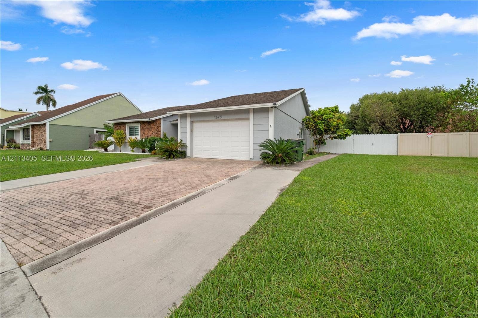 1675 S Goldeneye Lane, Homestead, FL 33035 Single-story exterior featuring a paver driveway, an attached garage, and perimeter vinyl fencing