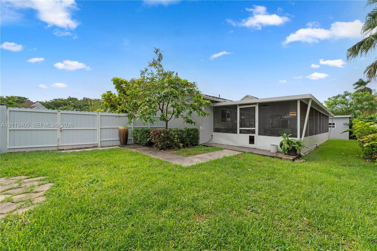 1675 S Goldeneye Lane, Homestead, FL 33035 Backyard featuring a screened-in lanai, concrete walkway, and perimeter privacy fencing