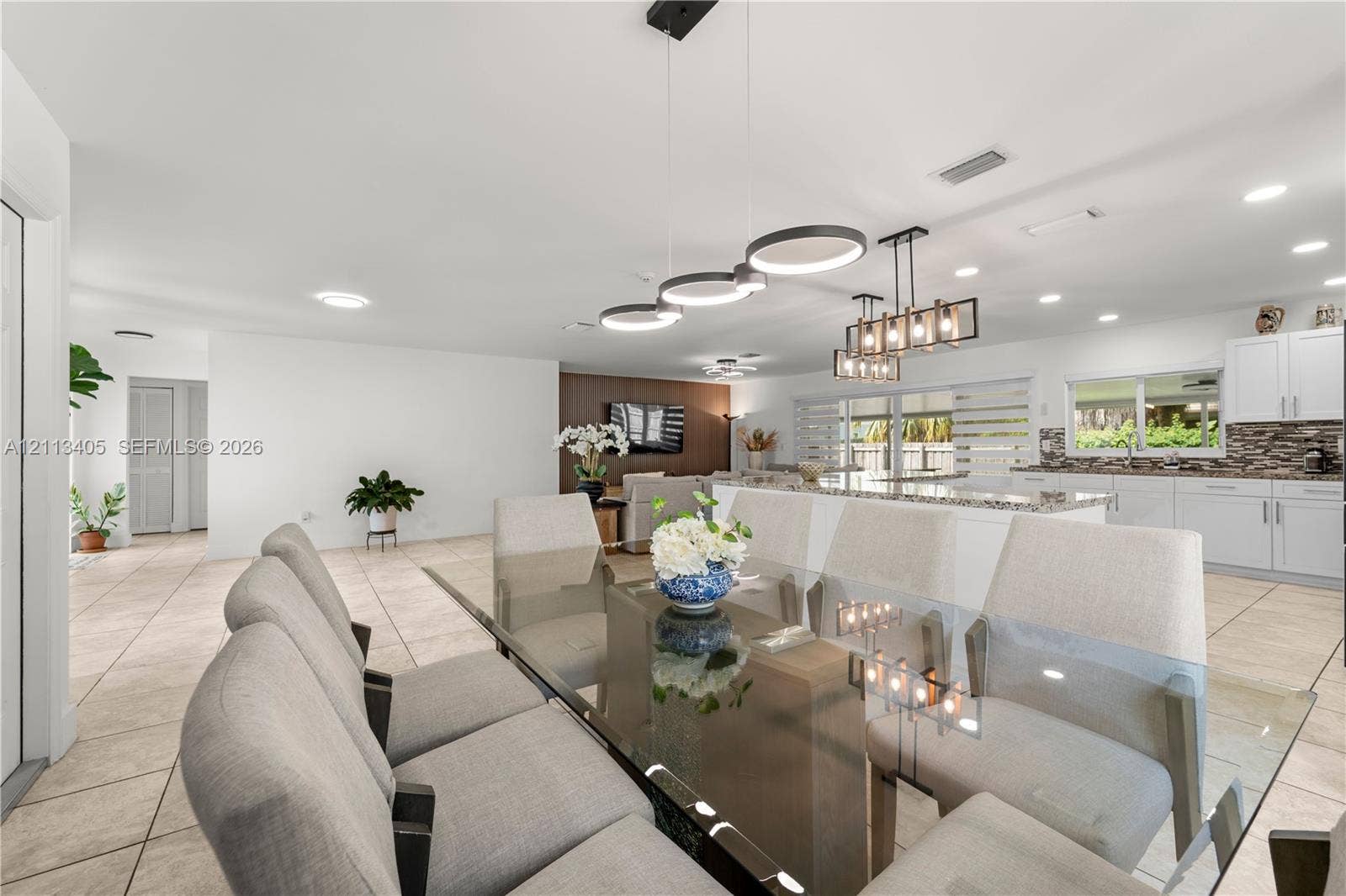 1675 S Goldeneye Lane, Homestead, FL 33035 Open-concept living space featuring ceramic tile flooring, recessed lighting, modern geometric pendant chandeliers, white shaker-style cabinetry, and a stone-tiled backsplash