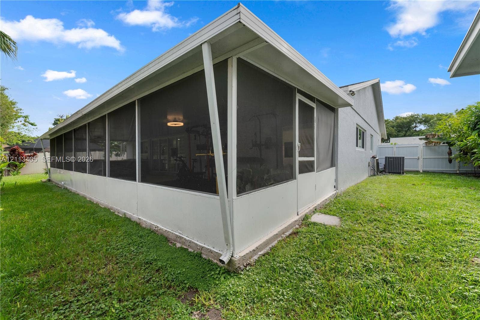 1675 S Goldeneye Lane, Homestead, FL 33035 Enclosed screened-in patio featuring white aluminum framing, a solid roof structure, and a perimeter lawn