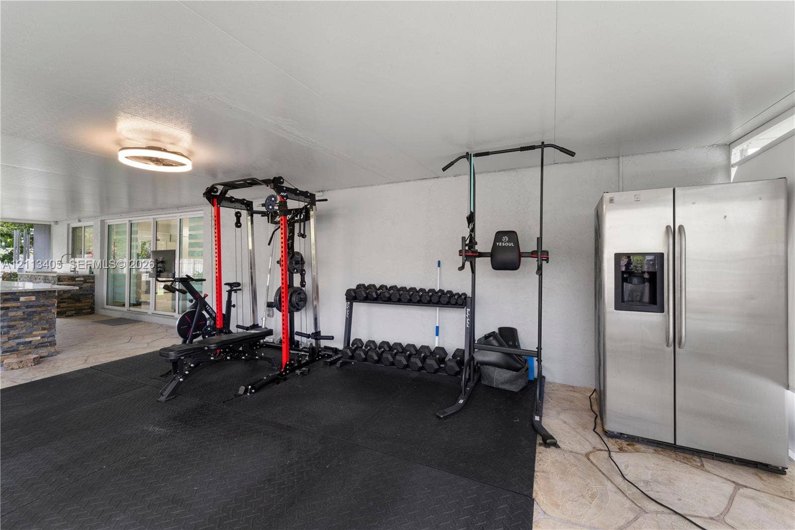1675 S Goldeneye Lane, Homestead, FL 33035 Covered outdoor area featuring stone-style flooring, a built-in stone-finish counter, sliding glass doors, and a ceiling-mounted light fixture