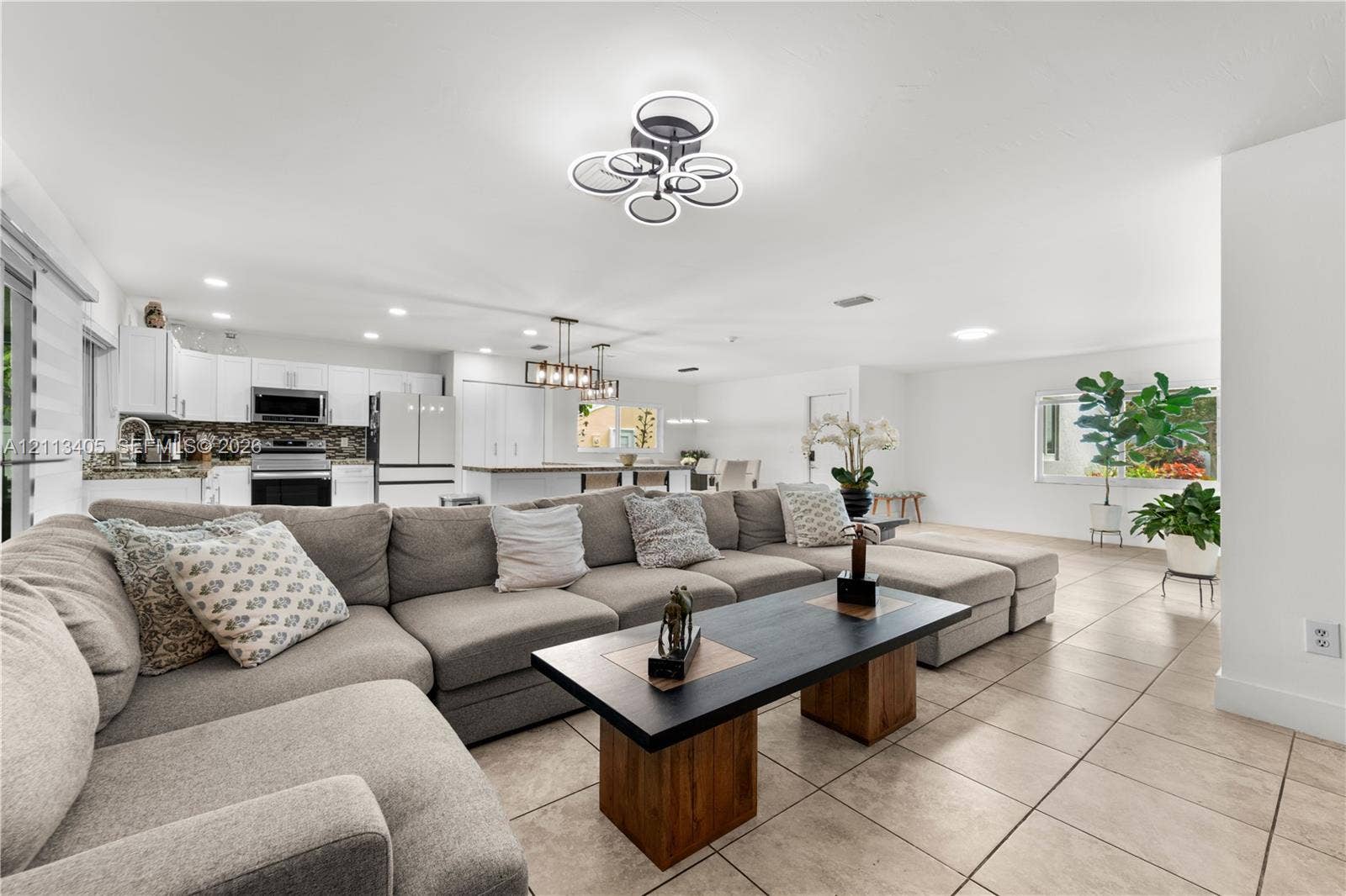 1675 S Goldeneye Lane, Homestead, FL 33035 Open-concept living space featuring ceramic tile flooring, recessed lighting, modern geometric chandelier, and white cabinetry