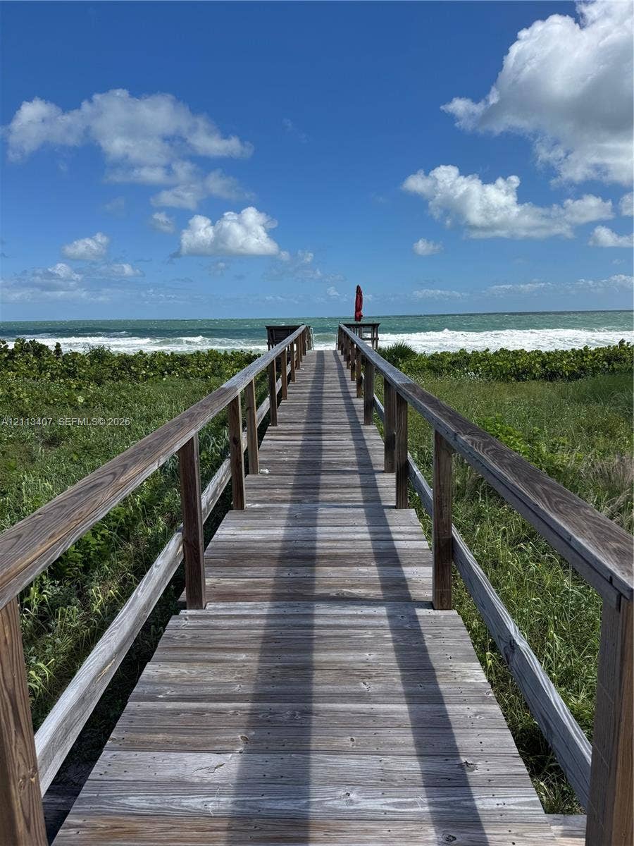 Elevated wooden boardwalk featuring timber railings and direct oceanfront access