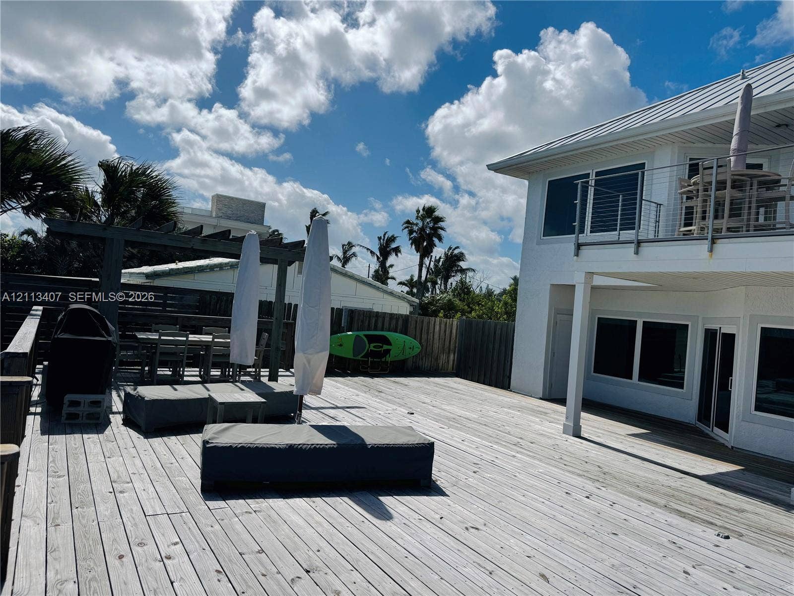 Spacious multi-level exterior decking featuring a custom wooden pergola, a second-story balcony with metal railings, and a metal roof