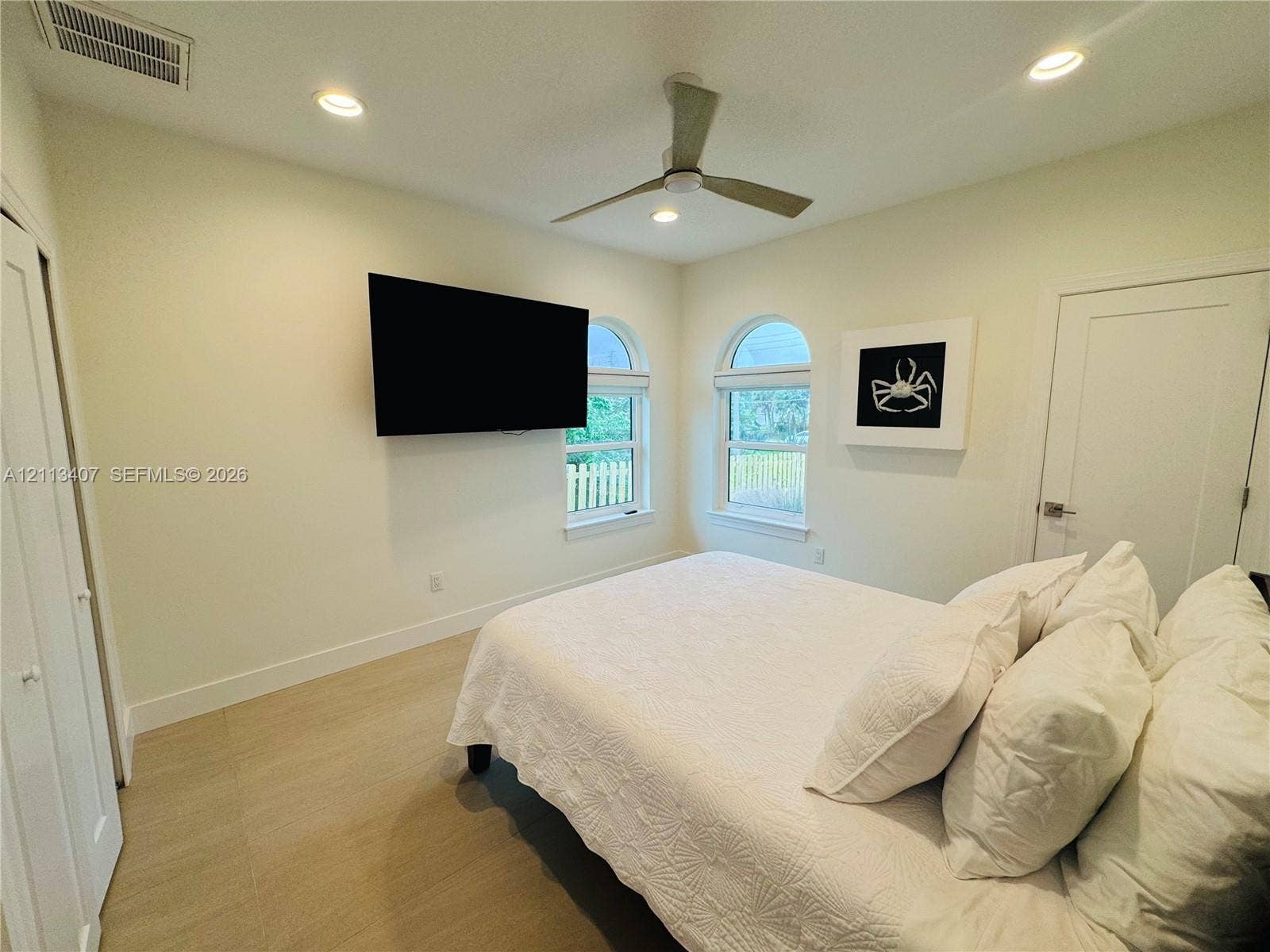 Room featuring neutral walls, wood-finish flooring, recessed lighting, a modern ceiling fan, and arched windows