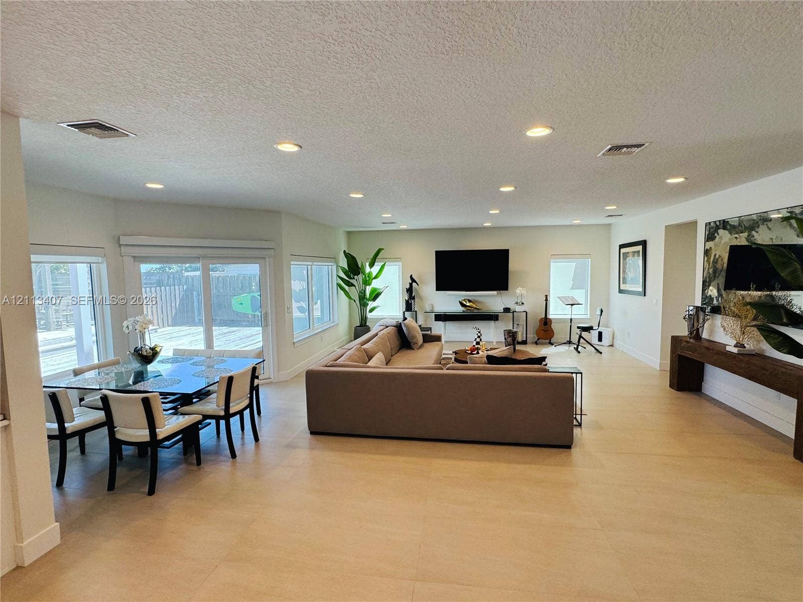 Open concept living area featuring large-format tile flooring, recessed lighting, and sliding glass doors