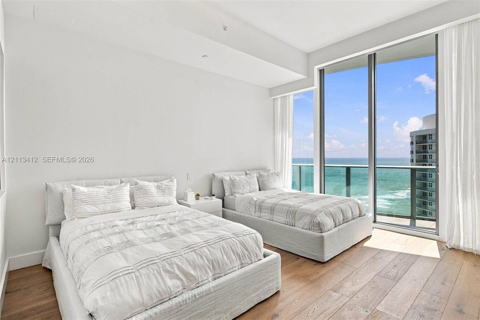 17475 Collins Avenue, #1802, Sunny Isles Beach, FL 33160 Floor-to-ceiling windows, wood-finish flooring, and direct ocean water backdrop