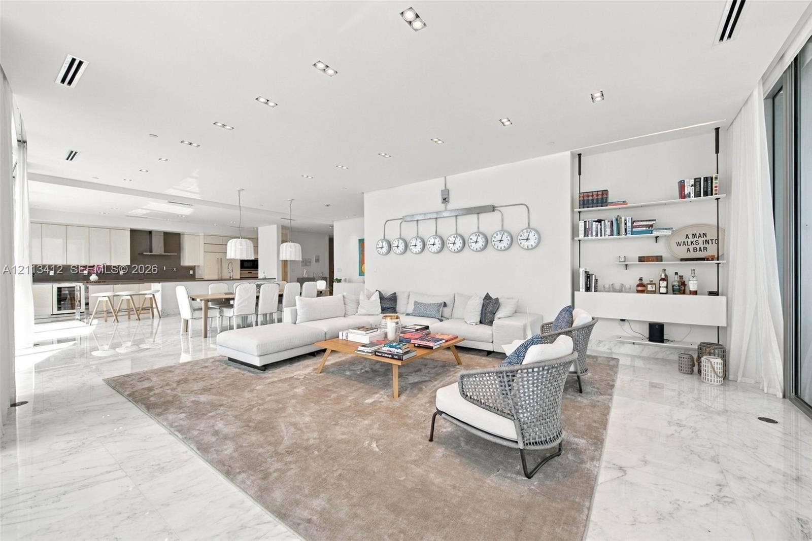 17475 Collins Avenue, #1802, Sunny Isles Beach, FL 33160 Open-concept interior featuring light-toned stone flooring, recessed ceiling lighting, and a wall-mounted shelving unit with integrated cabinetry
