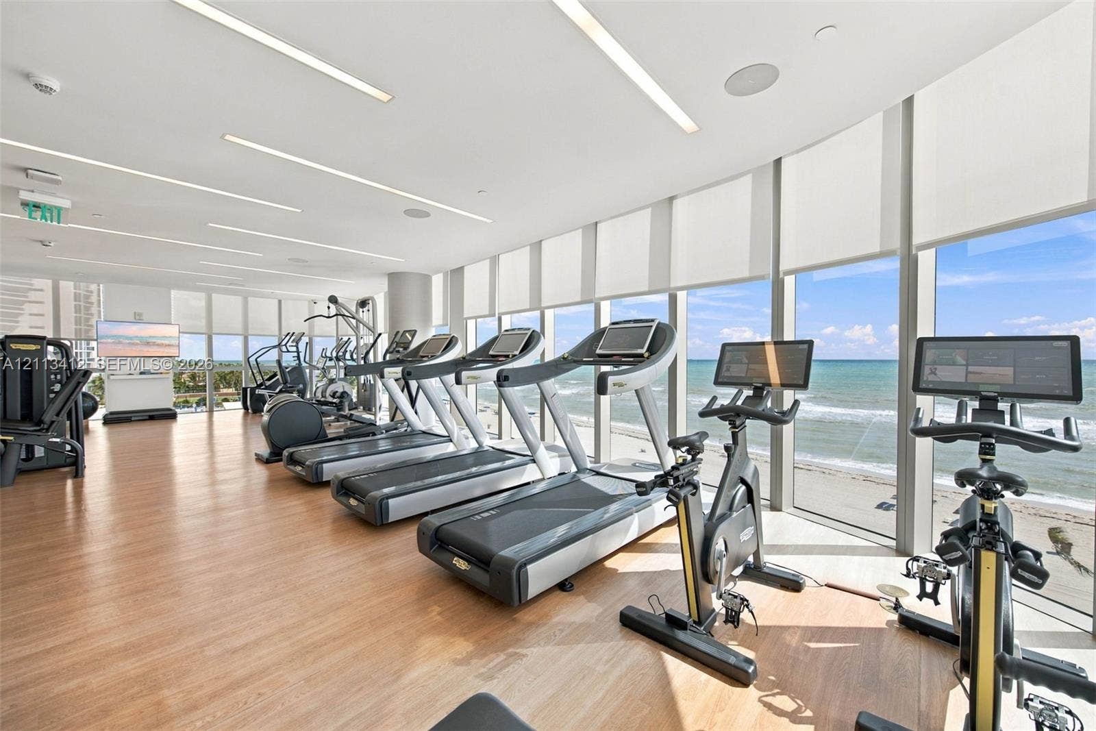 17475 Collins Avenue, #1802, Sunny Isles Beach, FL 33160 Fitness center featuring wood-finish flooring, floor-to-ceiling windows, and recessed linear lighting, with direct ocean backdrop