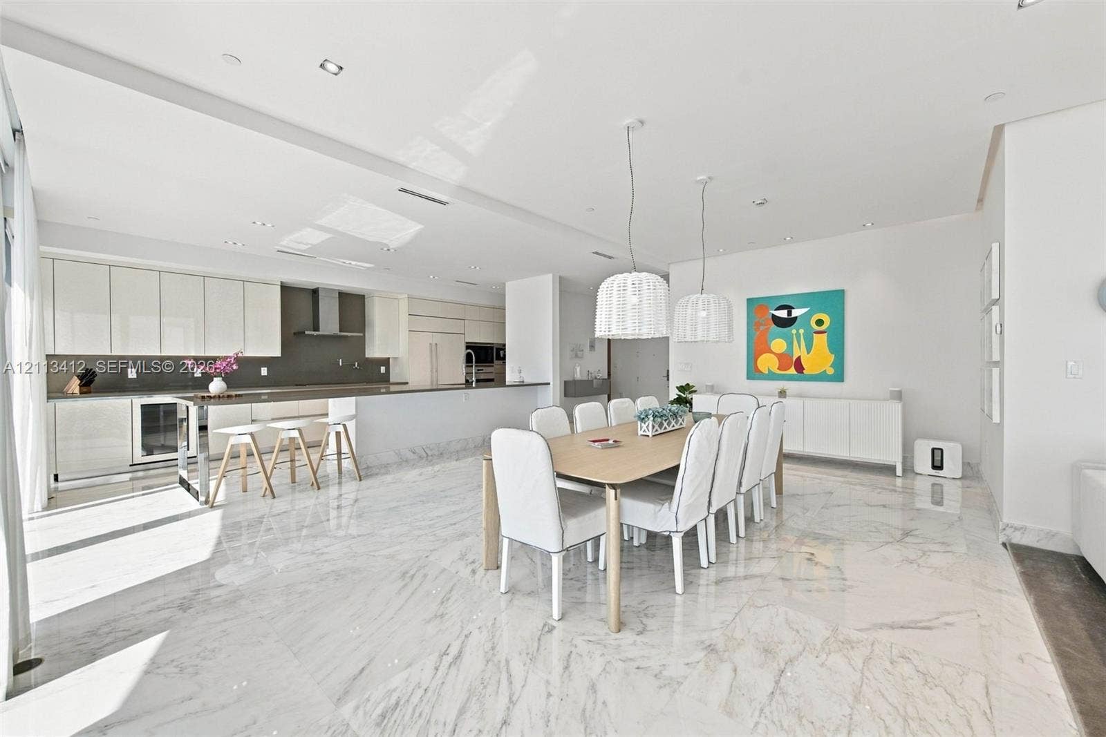 17475 Collins Avenue, #1802, Sunny Isles Beach, FL 33160 Open-concept kitchen and dining area featuring stone-finish flooring, high-gloss cabinetry, stainless steel range hood, built-in refrigerator, and dual pendant lighting fixtures