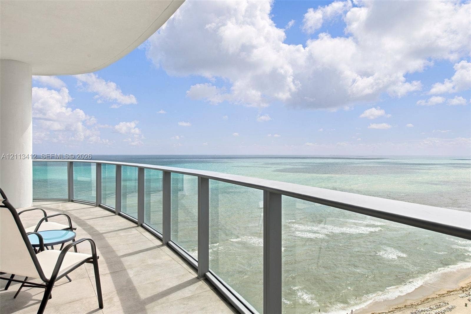 17475 Collins Avenue, #1802, Sunny Isles Beach, FL 33160 Curved balcony featuring neutral stone-finish flooring and a glass-paneled railing