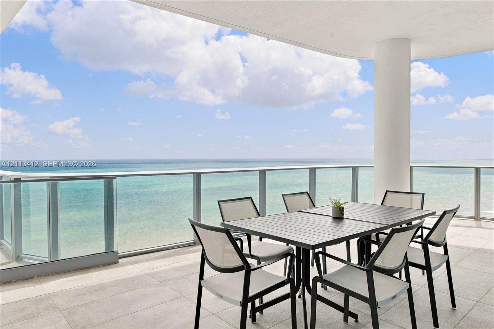 17475 Collins Avenue, #1802, Sunny Isles Beach, FL 33160 Covered balcony featuring oversized stone-style tile flooring, glass panel railings, and a structural support column