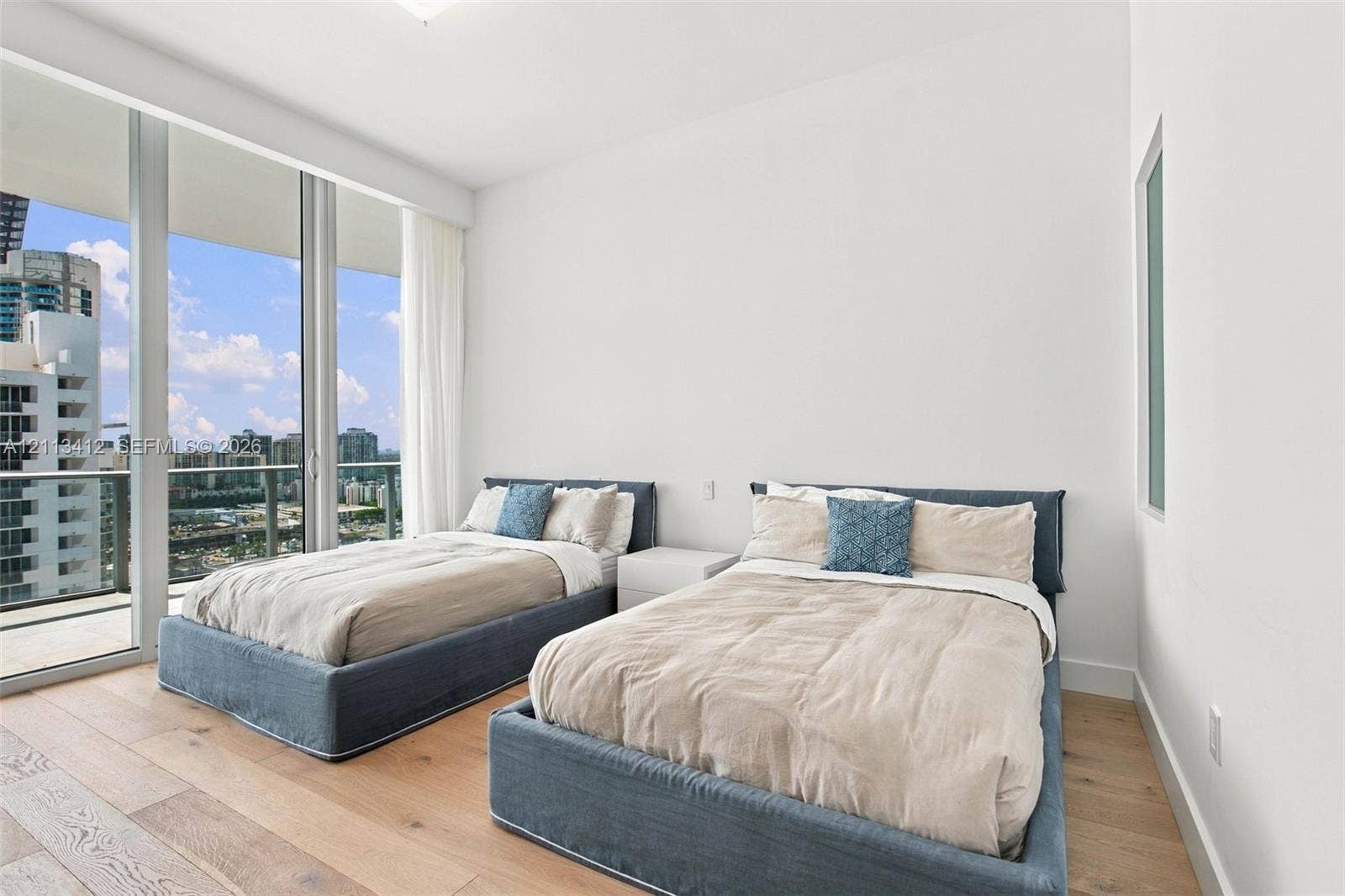 17475 Collins Avenue, #1802, Sunny Isles Beach, FL 33160 Floor-to-ceiling glass windows, wide-plank wood-finish flooring, and a private balcony with glass railing